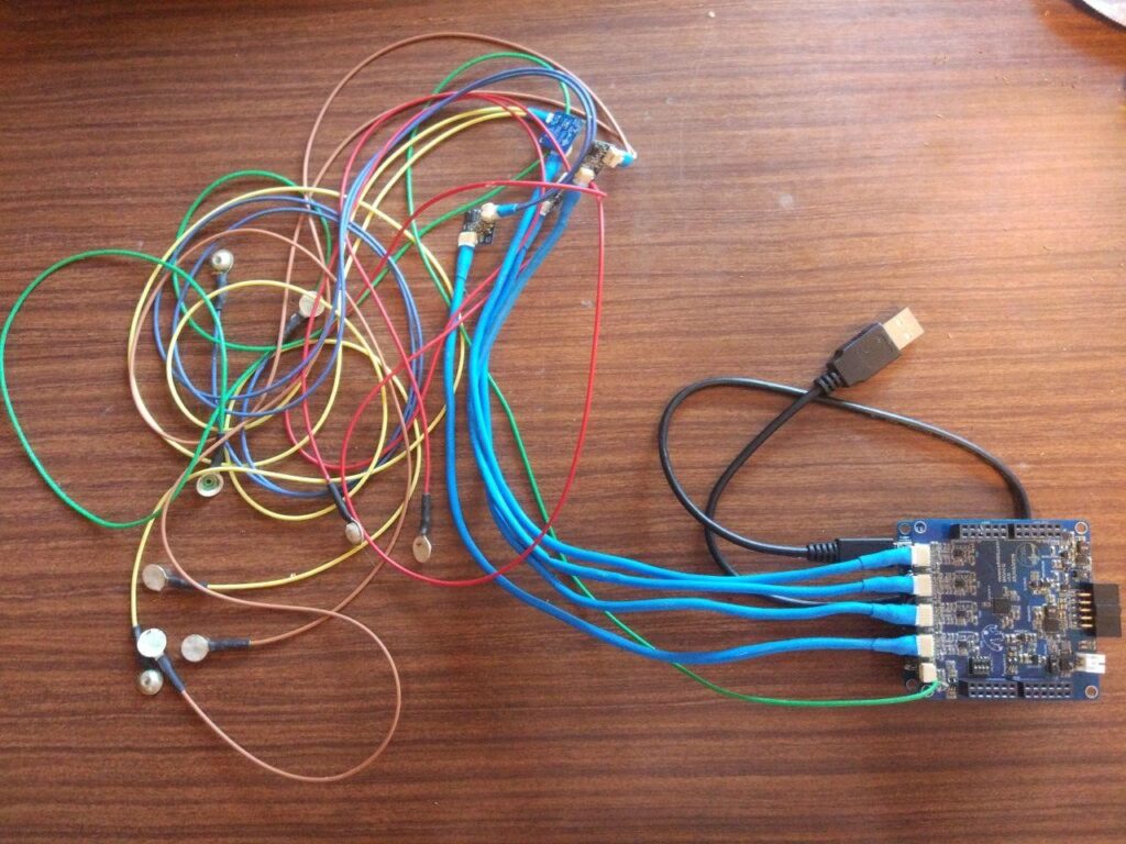 Picture of the hardware used for sEMG acquisition. On the left the electrodes, on top of the image a preamplifier and on the bottom right corner the stack of PCBs composed of the microcontroller and the ADC.
